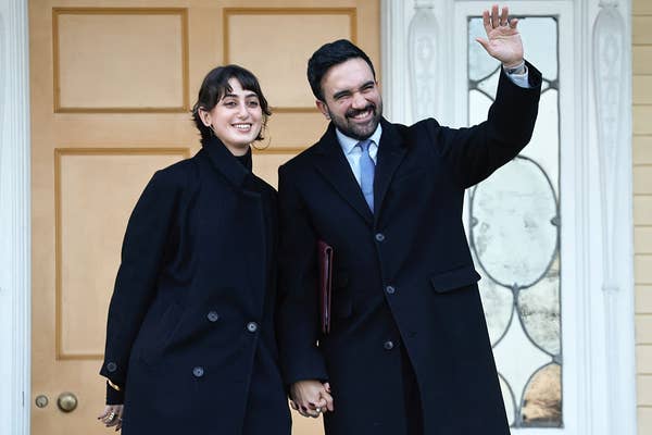 couple holding hands black coats waving.jpg