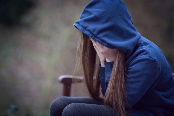 crying girl in blue hoodie covering face