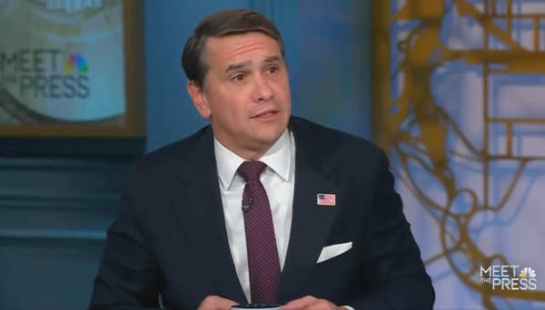 man in suit listening during news segment