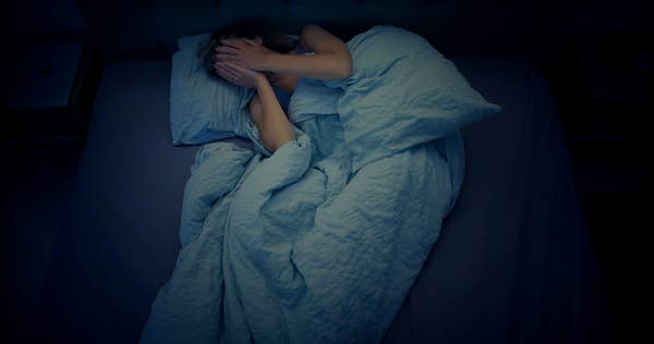 person covering face in bed nighttime distress