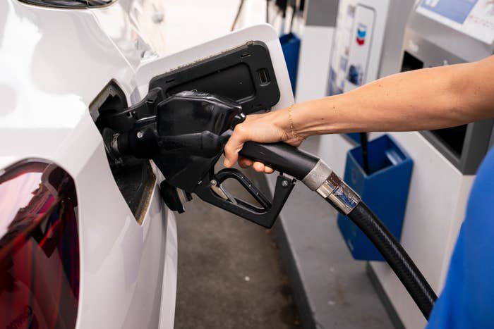 person refueling white car gas pump.jpg
