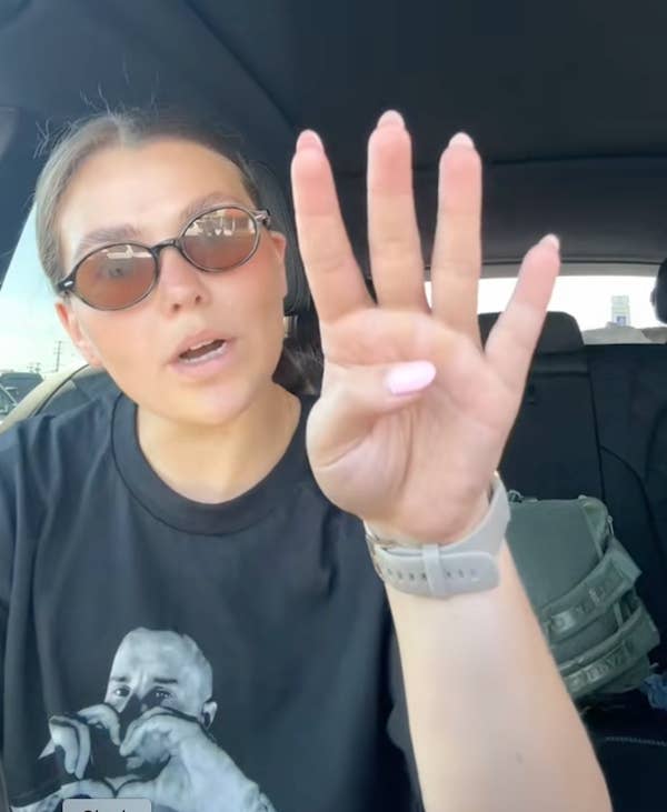 woman holding up four fingers in car